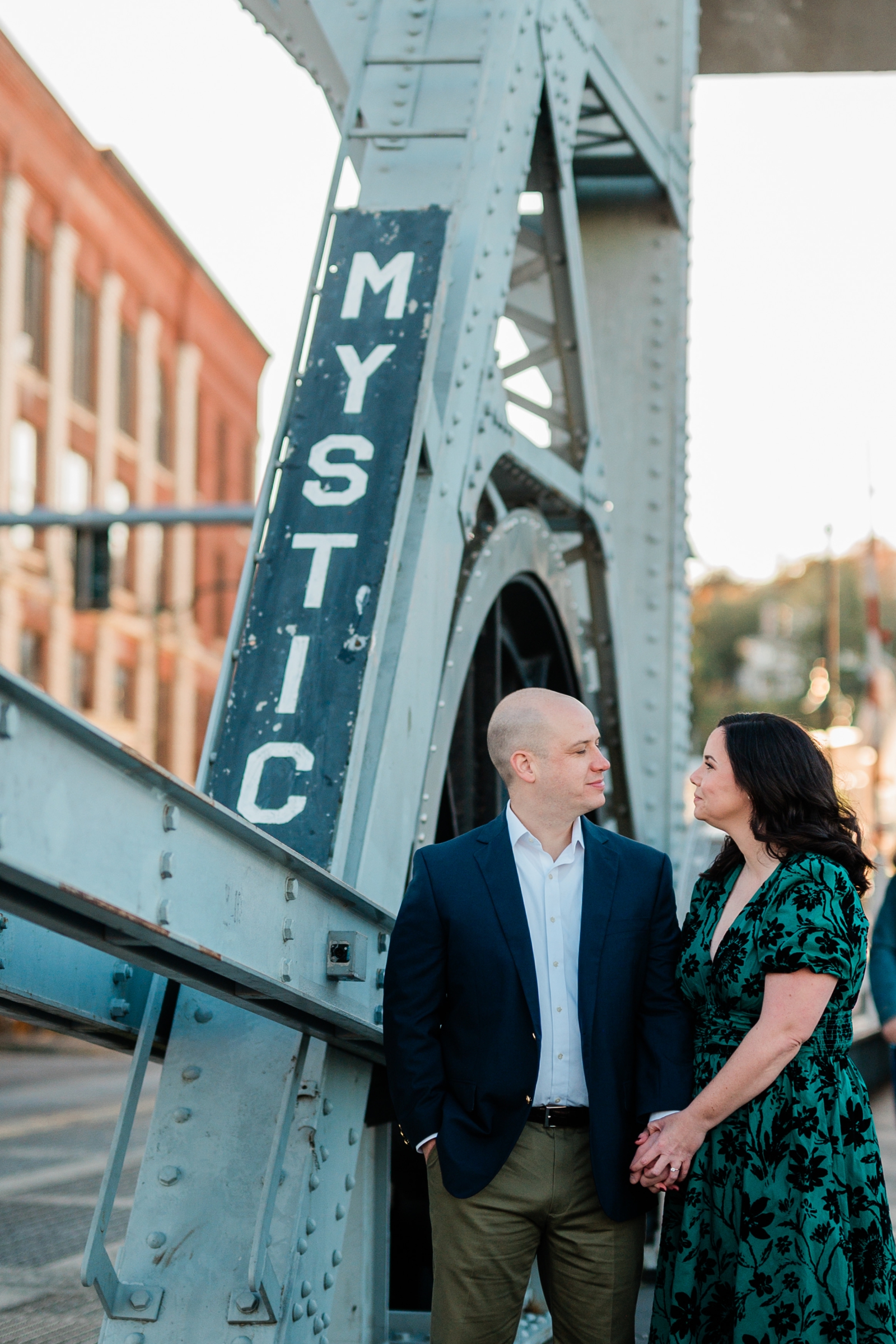 An engaged couple stands on the Mystic, CT drawbridge for their engagement photos