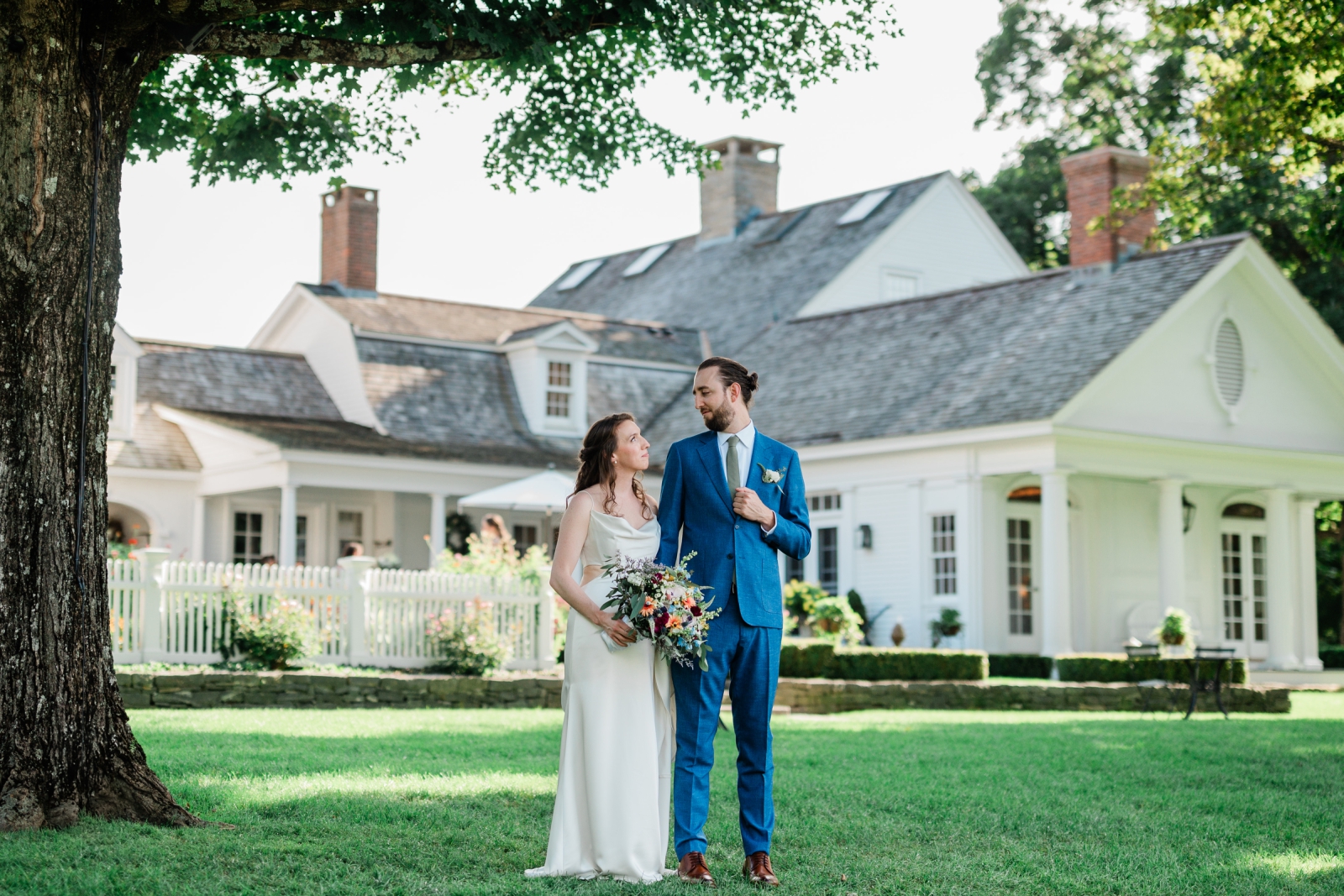 A couple stands together outside the farmhouse at Smith Farm Gardens