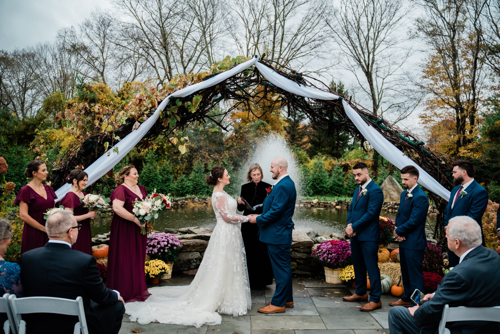 A couple stands beneath a trellis with white fabric during their fall wedding ceremony at the Salem Herbfarm