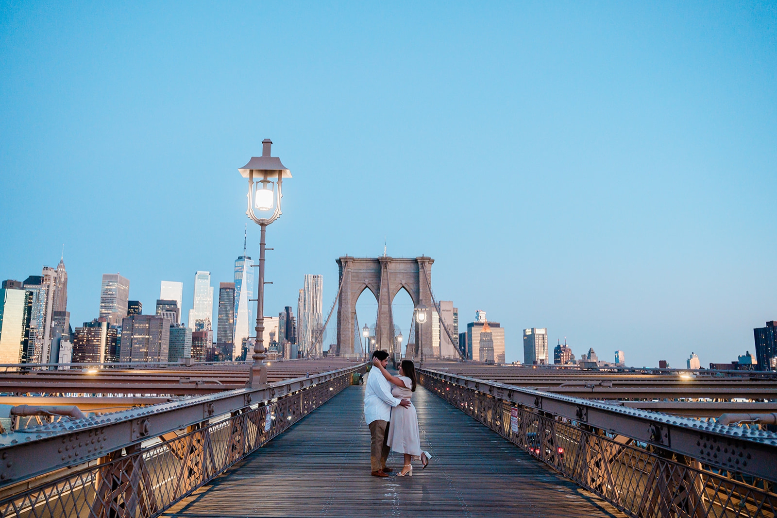 A couple stands alone on the Brooklyn Bridge right before dawn