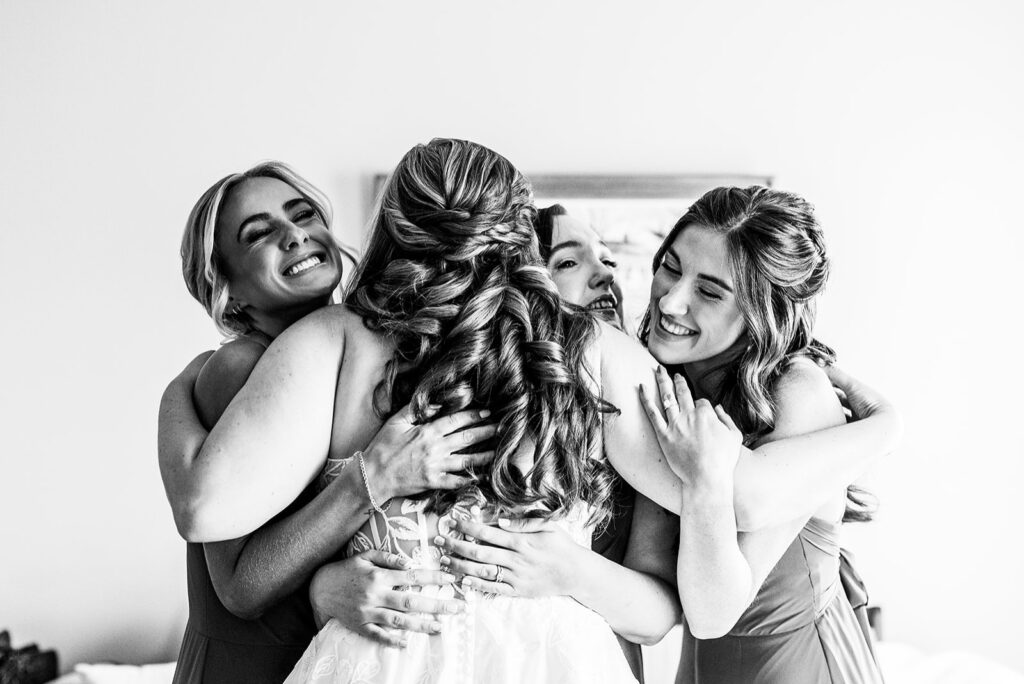 A black and white photo of a bride hugging three of her bridesmaids