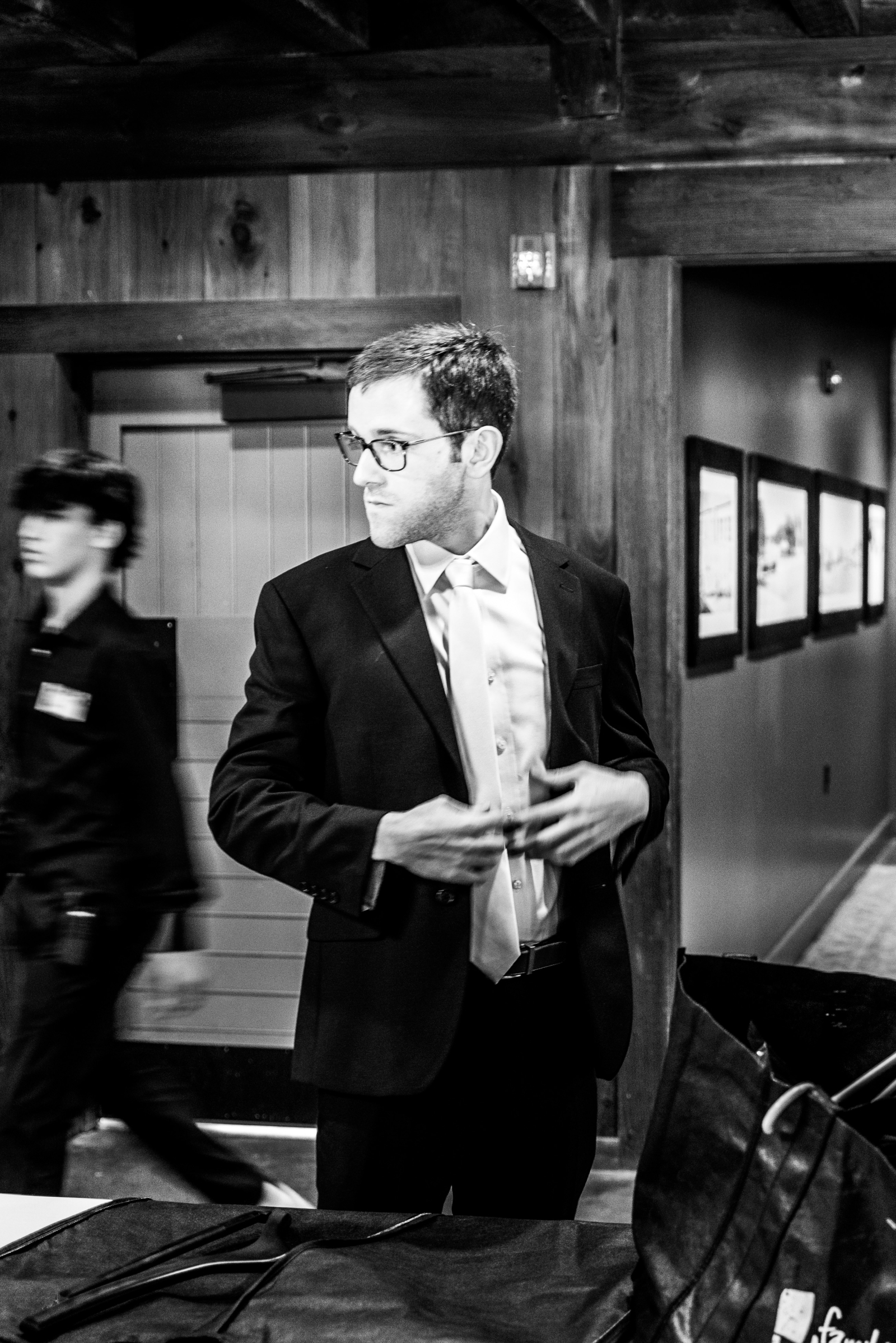 A black and white photo of a groom in a navy suite with a pearl colored tie