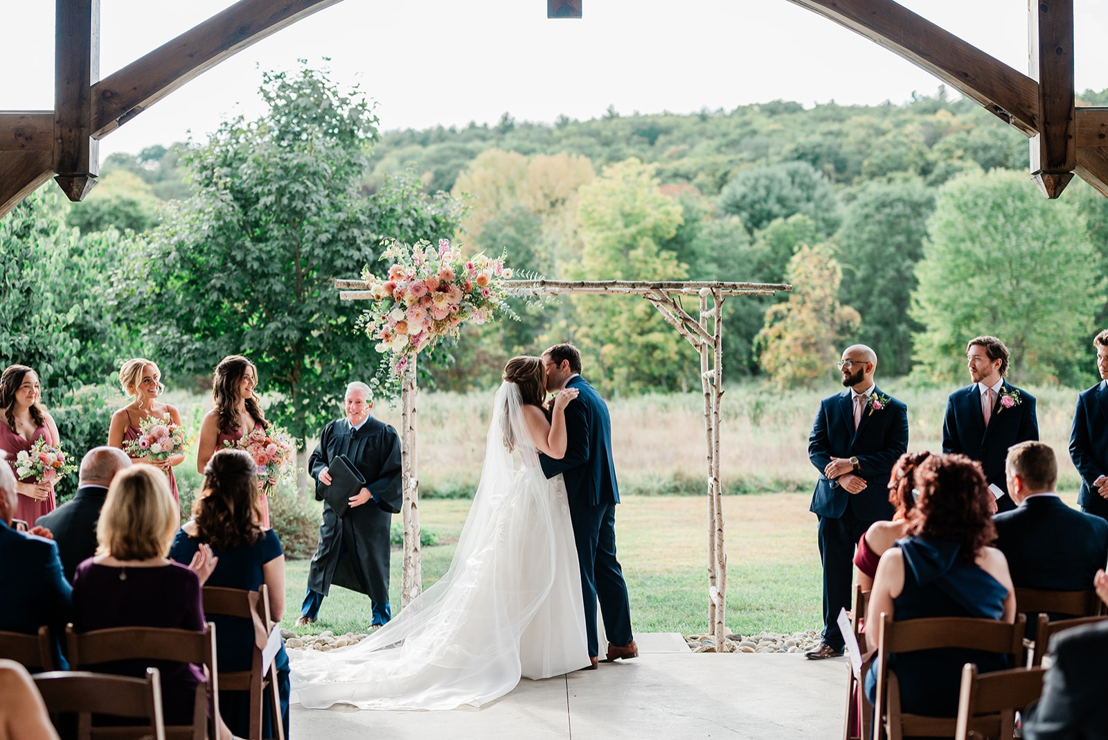 A bride and groom share a first kiss beneath the pavilion at Quonquont Farm
