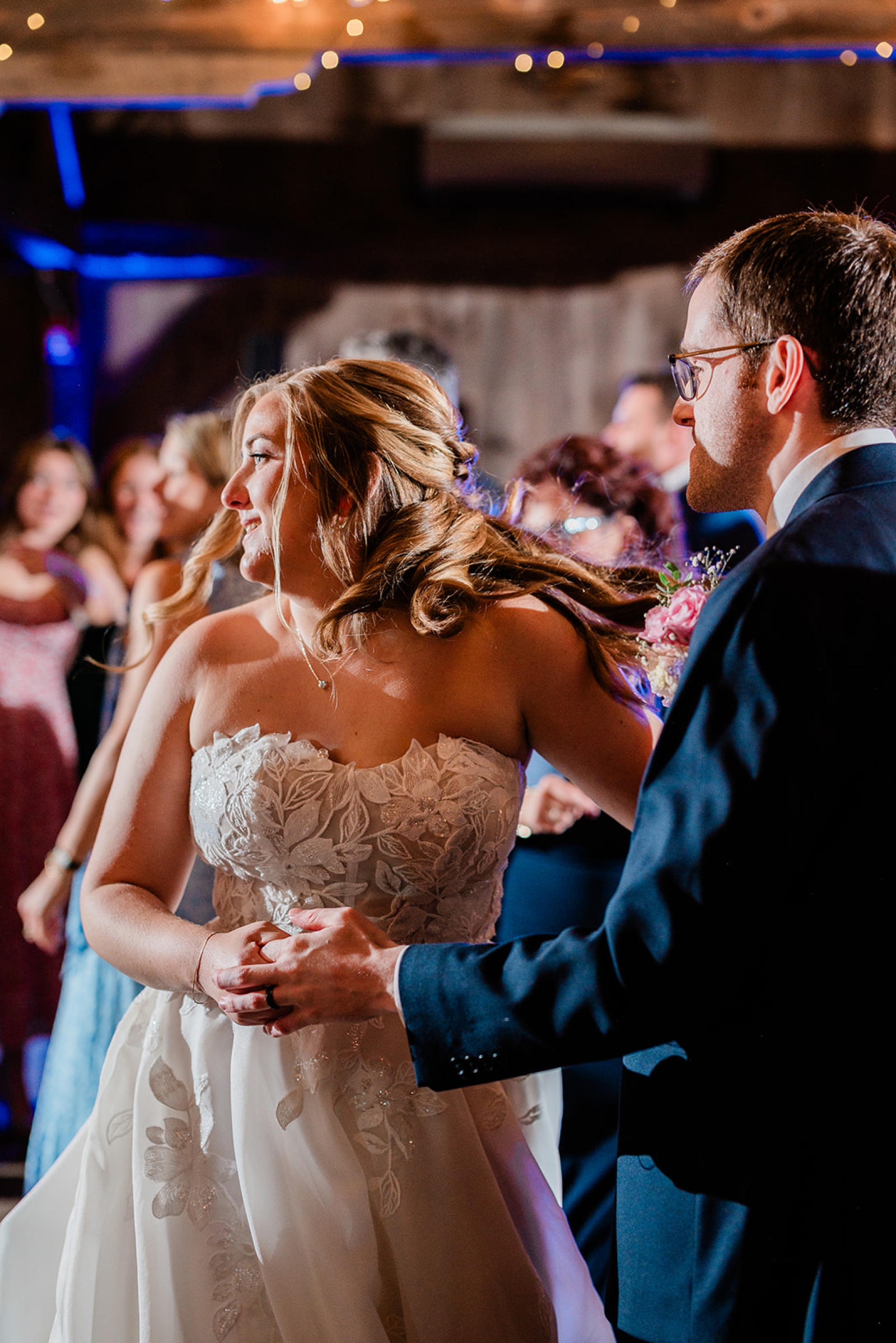 A bride and groom dance surrounded by guests at their wedding reeption