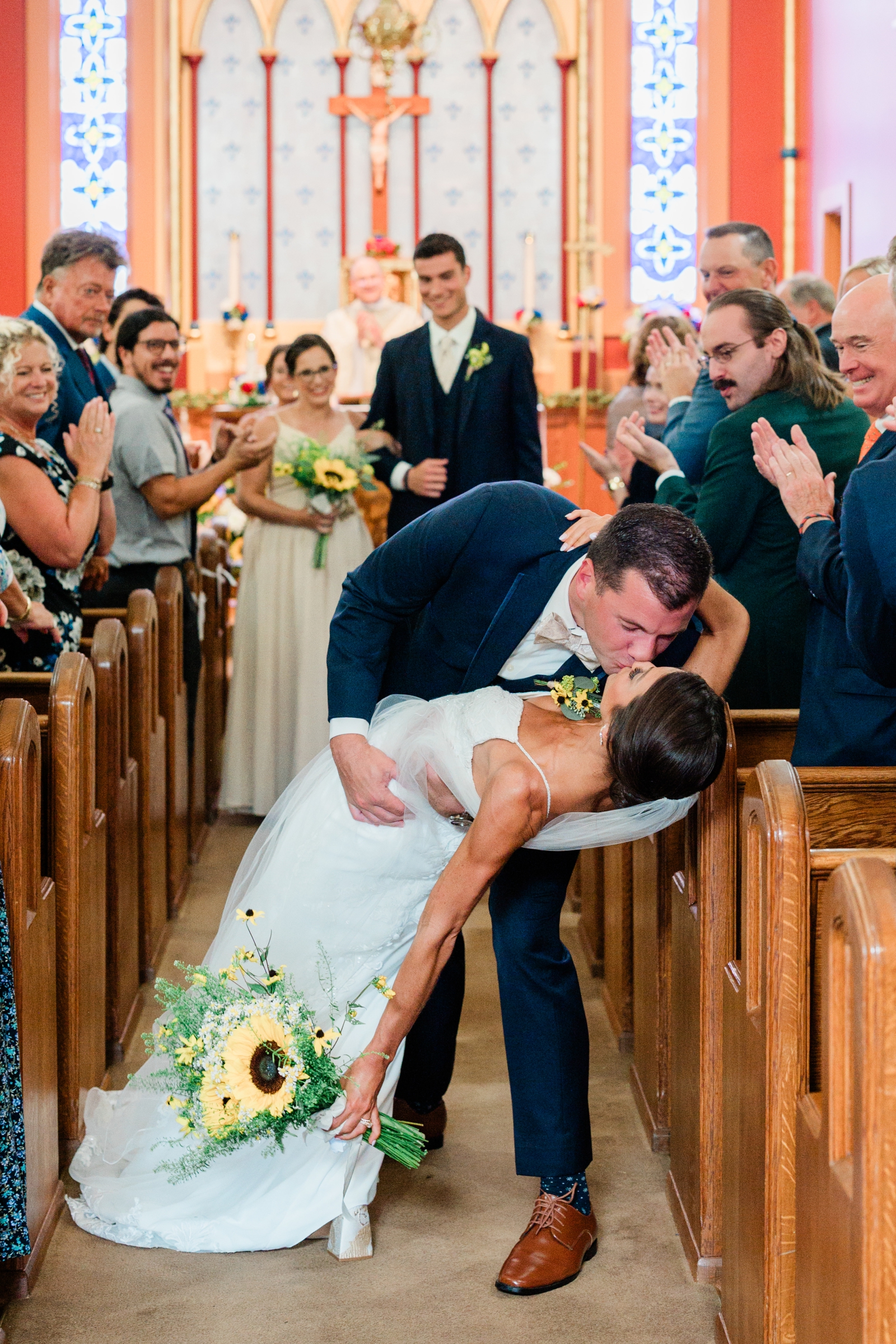 A bride and groom kiss as they walk back up the aisle after their wedding ceremony