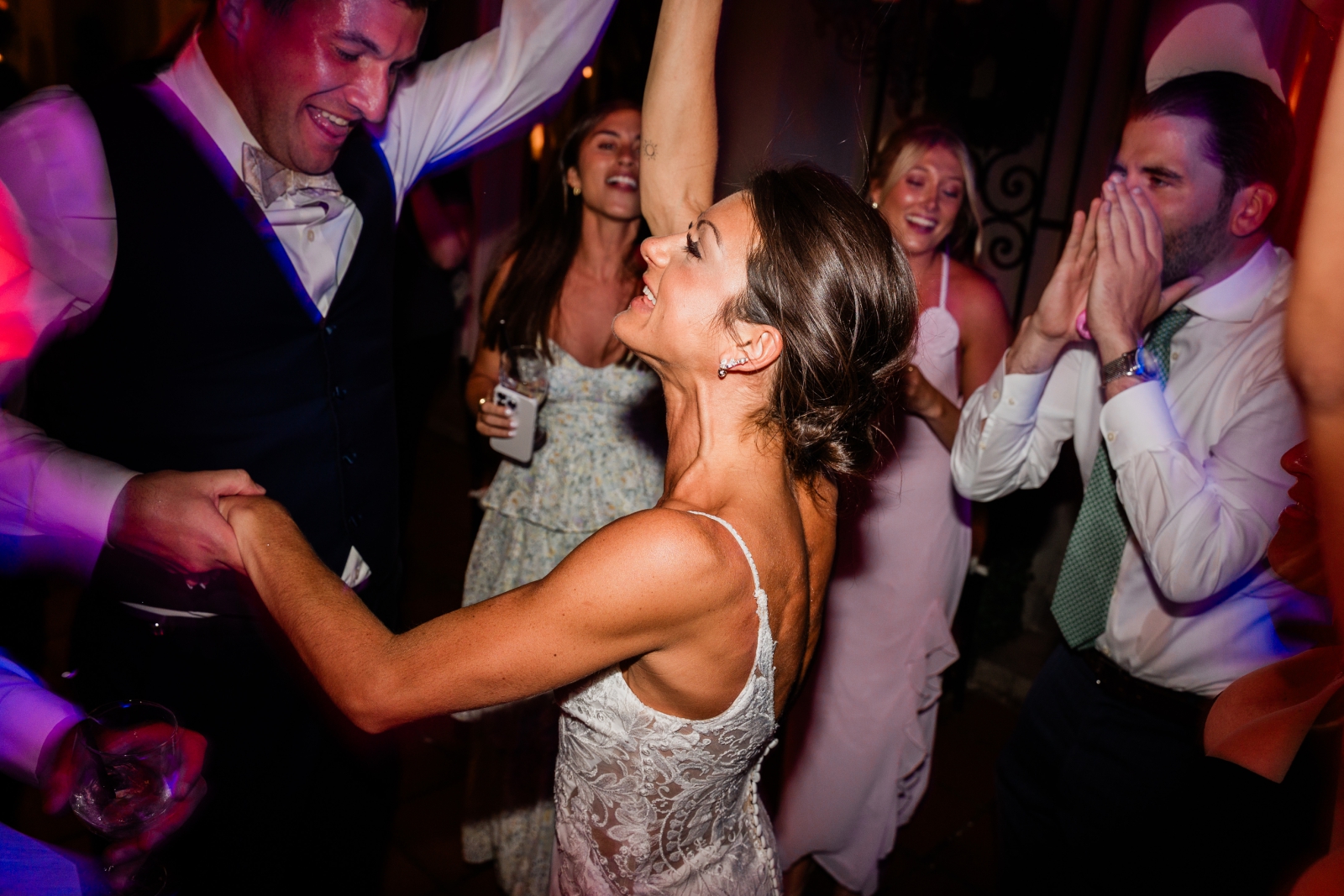 A bride and groom hold each other in the middle of a crowded dance floor at Lord Thompson Manor