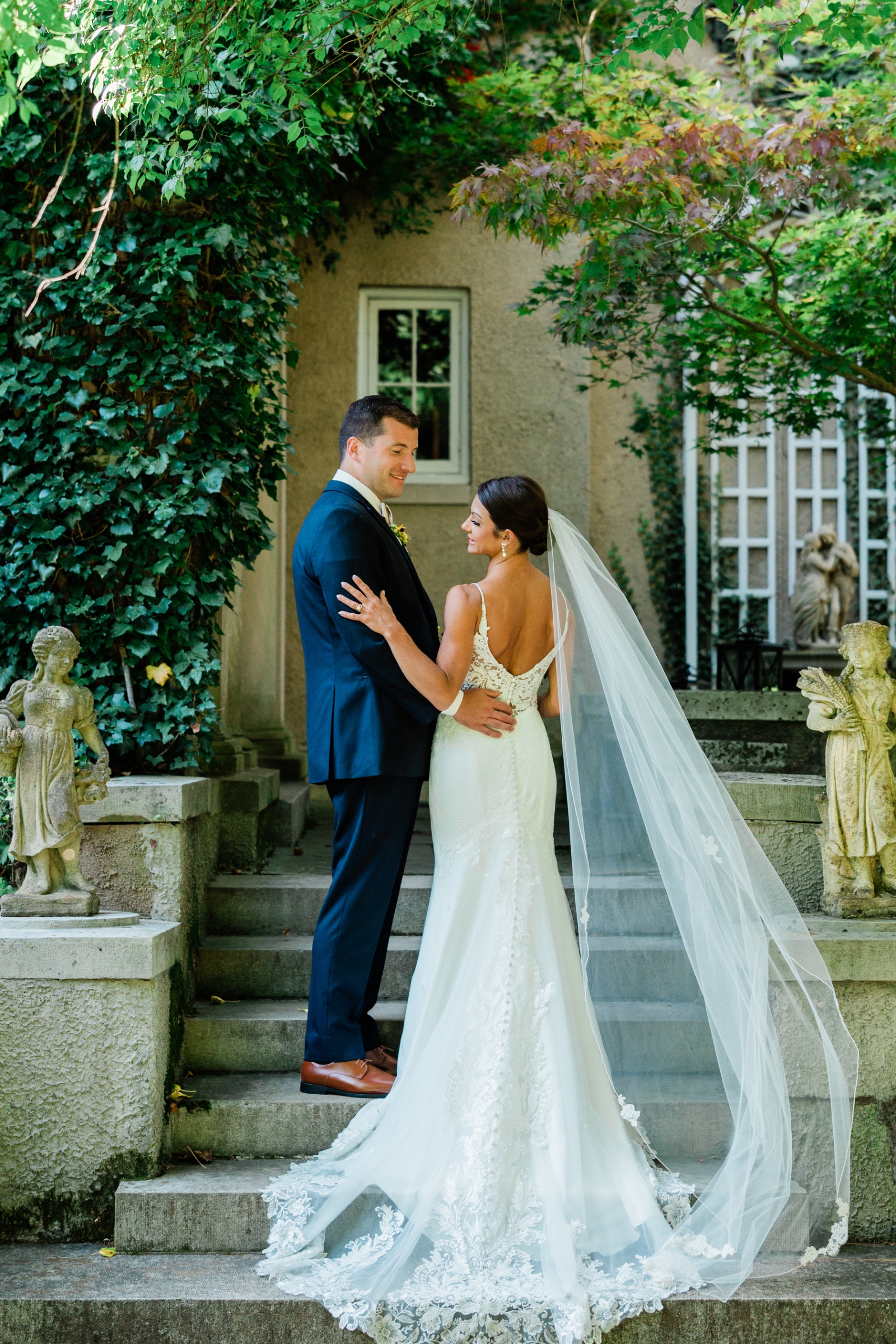 A bride and groom stand on the stairs outside of Lord Thompson Manor in Thompson, Connecticut