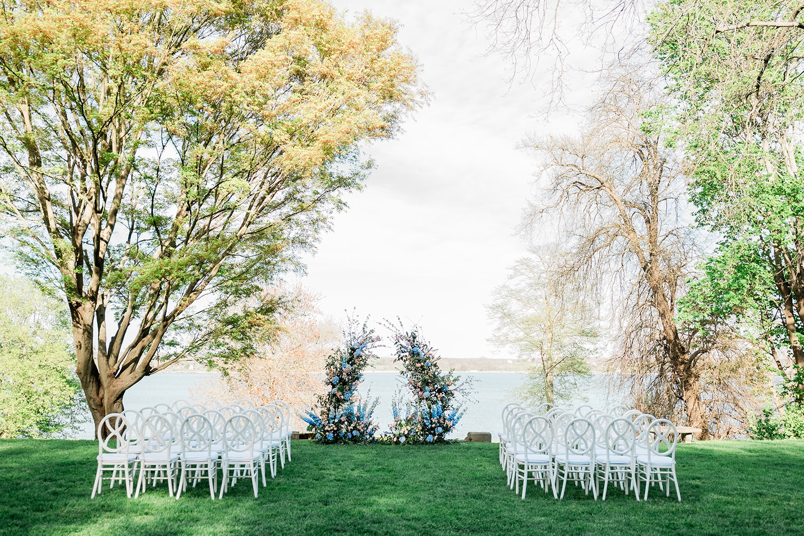 A ceremony with white chairs and blue, pink, and green florals at Glen House Manor