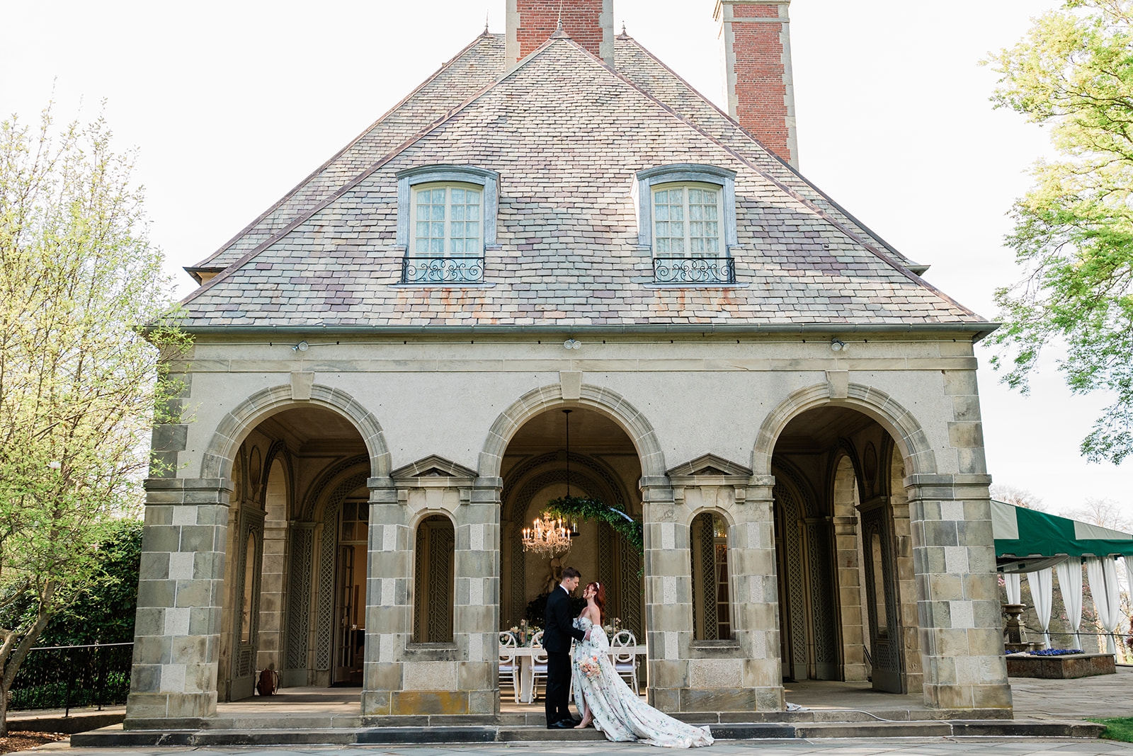 A bride and groom stand in front of the archways of the Glen Manor House courtyard
