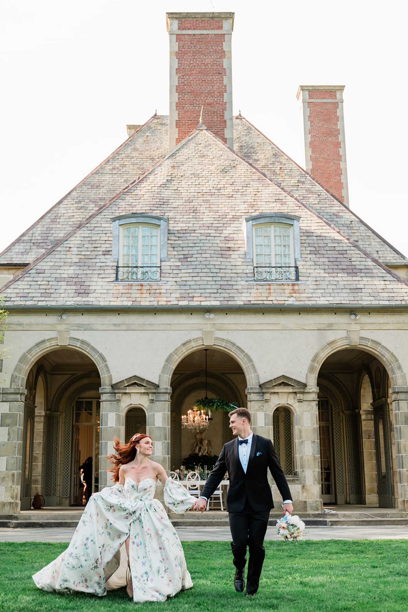 A bride and groom frolicking in front of the stone courtyard at Glen Manor Hotel